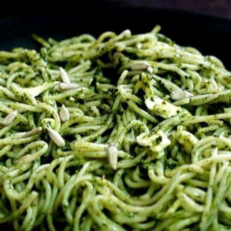 spaghetti in spinach sauce sunflowder seeds on top 